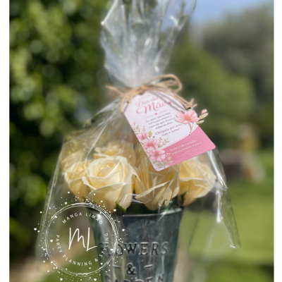 Vaso metálico com flores artificiais amarelas e cartão rosa em embalagem plástica