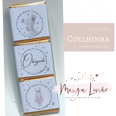 Três chocolates embrulhados com papel branco decorado com coelhos e a palavra 'Obrigado'.