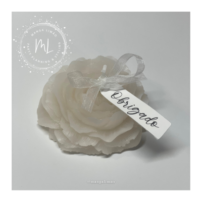 Vela branca em forma de flor decorativa com etiqueta 'Obrigado' e laço prateado