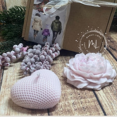 Velas decorativas rosa em formato de coração e flor sobre mesa de madeira com caixa ao fundo