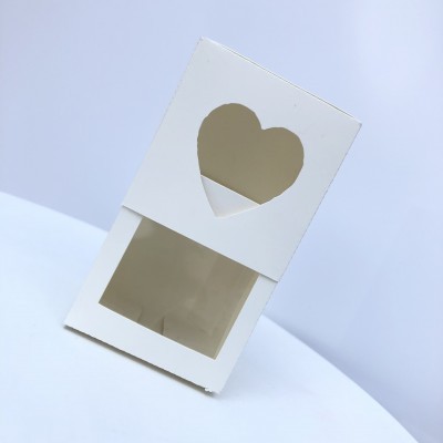 Caixa branca com janelas em forma de coração e retângulo