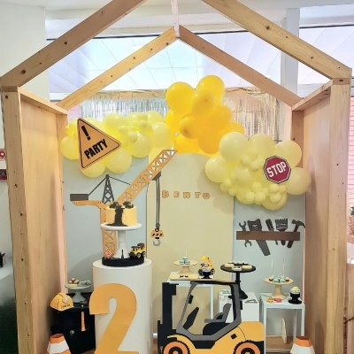 Decoração de festa temática construção com balões amarelos e elementos em madeira e plástico