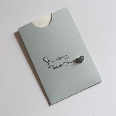 Envelope cinzento claro com texto em português e dois pequenos corações pretos