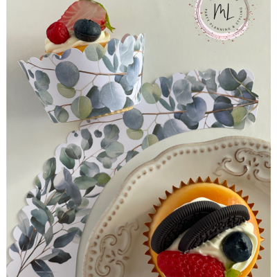 Embalagens para cupcakes com padrão de folhas verdes e cupcakes decorados em prato branco