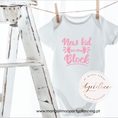 Body de bebé branco com texto cor-de-rosa pendurado junto a banco de madeira branca envelhecida