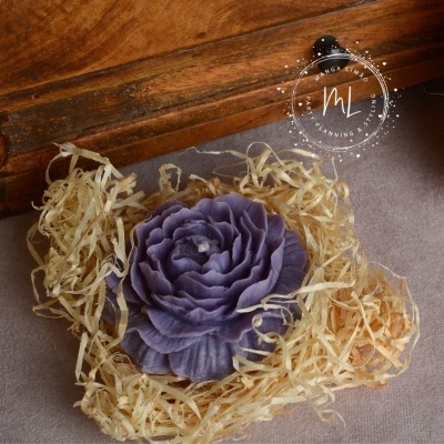 Flor decorativa roxa em palha seca sobre tecido cinzento