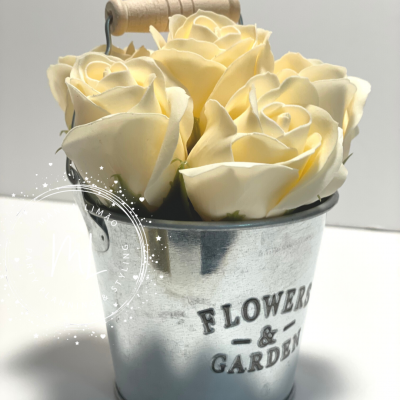 Balde metálico com flores artificiais creme e texto 'FLOWERS & GARDEN'