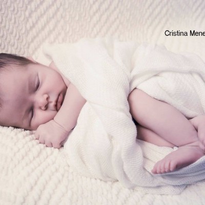 Bebé recém-nascido dormindo envolto em cobertor branco de malha