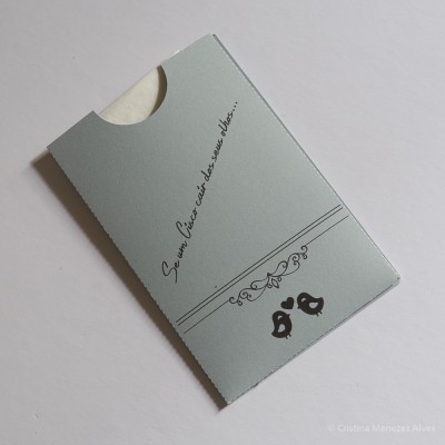 Embalagem cinza clara em cartão com dois pássaros desenhados e texto cursivo preto