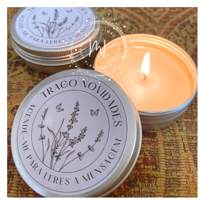 Velas em latas metálicas prateadas com tampas decoradas com flores, borboletas e texto, uma vela acesa