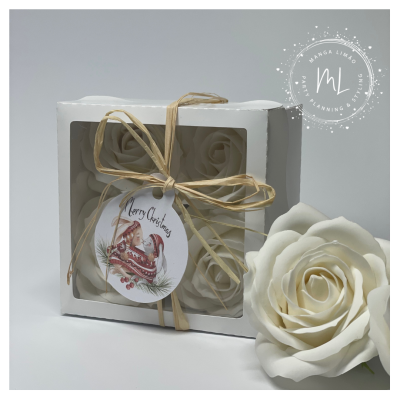 Caixa branca com quatro sabonetes em forma de rosa creme, decorada com fita de palha e etiqueta de Natal