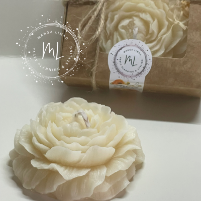 Vela decorativa branca em forma de flor ao lado de uma caixa de papel castanho com etiqueta branca