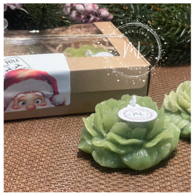 Vela verde em forma de flor ao lado de embalagem com rótulo de rosto natalício