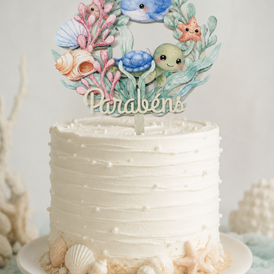 Bolo branco com decoração marinha e topo com palavra Parabéns e animais marinhos