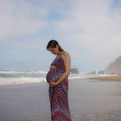 Mulher grávida com vestido longo padrão colorido na praia