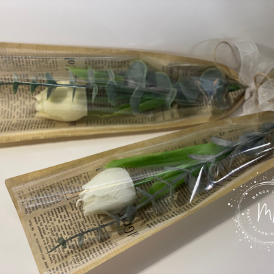 Duas rosas brancas embaladas em papel estilo jornal e plástico