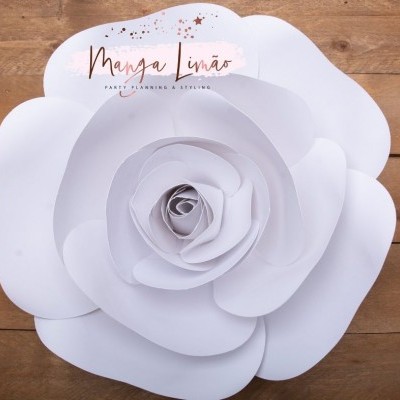 Flor decorativa branca de papel com várias pétalas sobre madeira