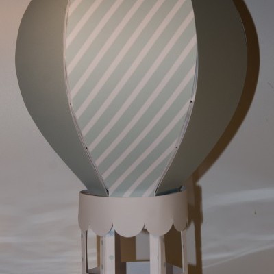 Modelo decorativo de balão de ar quente em papel com riscas verdes e base branca com pontos