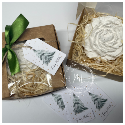 Caixa kraft com laço verde e sabonete branco em forma de flor com etiqueta de Natal