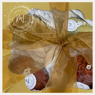 Caixa de presente amarela com laço dourado e quatro velas decorativas com etiquetas ML