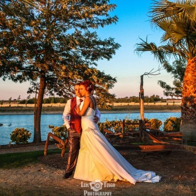 Casal de noivos ao ar livre junto a um lago ao pôr do sol