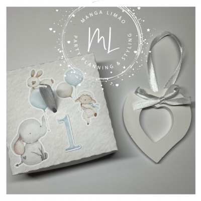 Caixa branca com decoração infantil e ornamento de coração branco com fita prateada