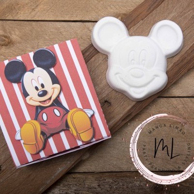 Sabonete Mickey Mouse branco ao lado da embalagem com imagem do personagem e selo MANGA LIMÃO numa superfície de madeira.