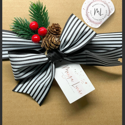Presente embrulhado em papel castanho com fita preta e branca às riscas e decoração natalícia.
