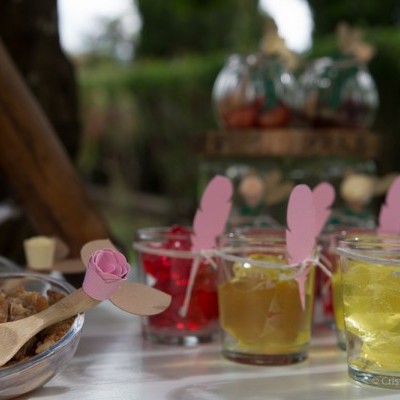 Copos com gelatina colorida e decoração de pássaros cor-de-rosa numa mesa branca ao ar livre