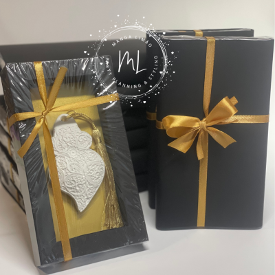 Presentes embalados em papel preto com fita dourada e ornamento branco decorativo