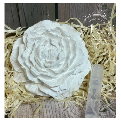 Flor decorativa branca com frasco transparente sobre palha e fundo de madeira