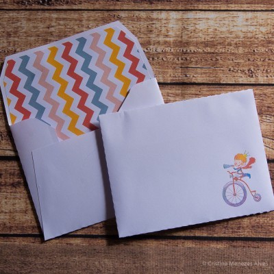 Dois envelopes brancos, um com padrão interior colorido e outro com ilustração de criança em bicicleta.