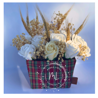 Arranjo com rosas artificiais brancas e espigas de trigo em vaso com tecido xadrez.