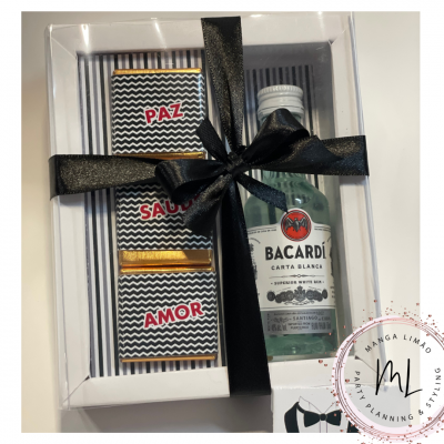Conjunto de presente com garrafa de Bacardi e barras de chocolate embaladas em caixa branca com fita preta