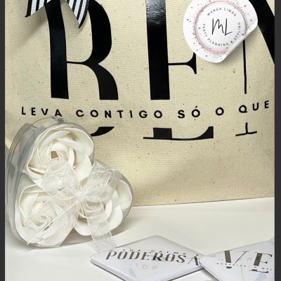 Saco de algodão cru com texto e autocolante, caixa coração com flores artificiais e dois quadrados com texto em superfície branca