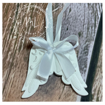 Ornamento branco em forma de anjo com laço de fita branca sobre madeira