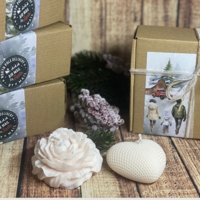 Caixas de cartão com etiquetas e velas decorativas em forma de flor e coração sobre mesa de madeira