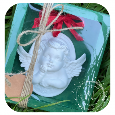 Anjo decorativo branco com fita vermelha numa embalagem verde com laço de corda sobre relva