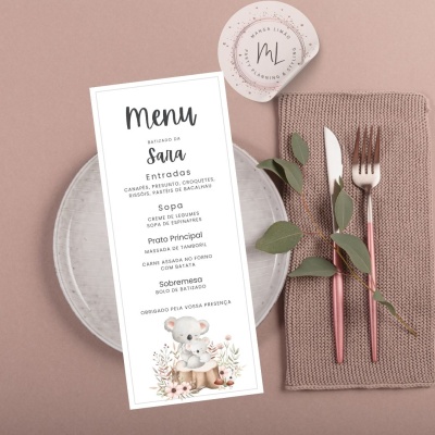 Menu de papel sobre prato com talheres e folhas verdes em fundo bege