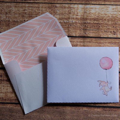 Envelope aberto e carta com ilustração de coelho e balão sobre fundo de madeira