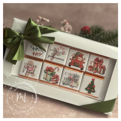 Caixa de bombons decorados com ilustrações de Natal e textos em português, com fita verde