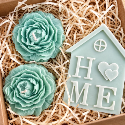 Conjunto de velas azuis em forma de flor e vela em forma de casa com palavra HOME em caixa de palha.