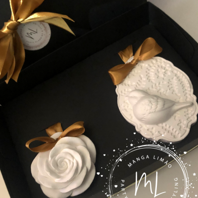 Sabonetes decorativos brancos em caixa preta com laços dourados e etiqueta da marca