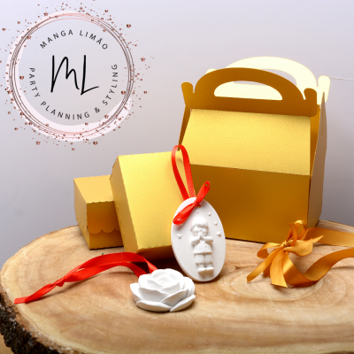 Caixas amarelas, fitas coloridas e enfeites brancos sobre madeira, com logótipo MANGA LIMÃO
