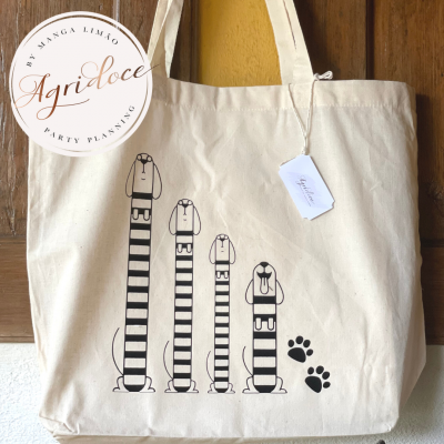 saco de tecido cru com estampa de cães listrados pretos e etiqueta pendurada