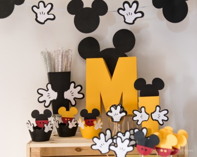 Decoração de festa com tema Mickey Mouse com recortes coloridos e copos decorativos