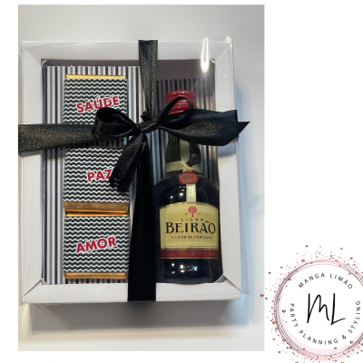 Conjunto de presente com garrafa de Licor Beirão e barras de chocolate embaladas, tudo dentro de caixa branca com laço preto.