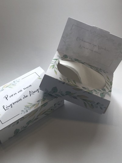 Caixas decoradas com folhas verdes, uma aberta contendo lenço branco