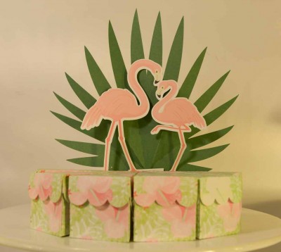 Caixa decorativa com recortes de flamingos cor-de-rosa e folhas verdes.