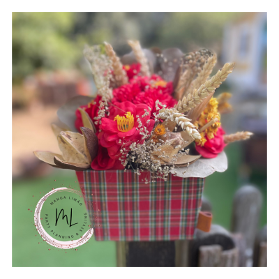 Arranjo floral vermelho com flores secas num vaso xadrez ao ar livre